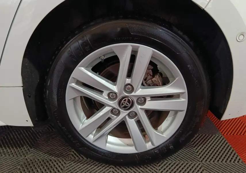 Gros plan sur la roue avant gauche blanche d'une Toyota Corolla hybride 2022 avec jante alliage argentée.