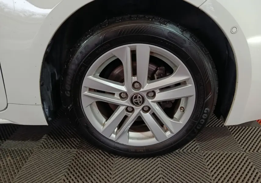 Gros plan sur la roue avant droite blanche d'une Toyota Corolla Hybride 2022 avec jante alliage et pneu Goodyear.
