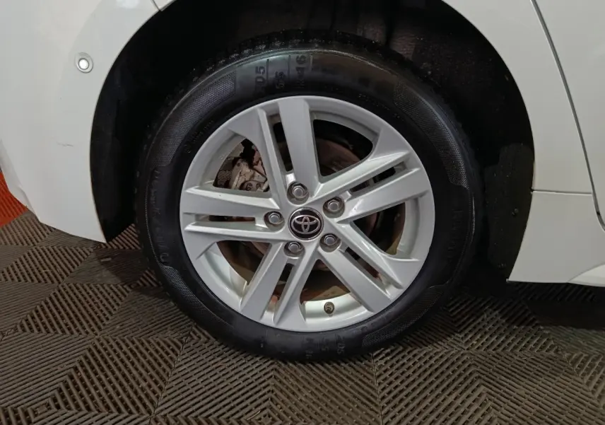 Gros plan sur la roue avant droite blanche de la Toyota Corolla Hybride 2022 avec jante alliage et logo Toyota central.