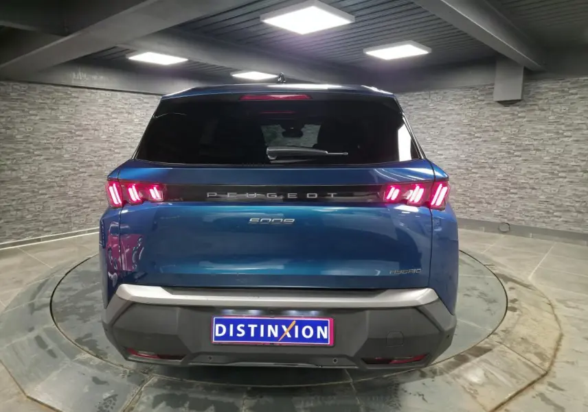 Vue arrière d'un Peugeot 5008 bleu métallisé 2025 avec feux arrière LED à trois griffes et bandeau noir laqué.