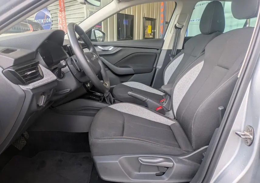 Vue intérieure côté conducteur de la Skoda Scala gris reflex 2025, avec sièges tissu bicolore et volant multifonction.