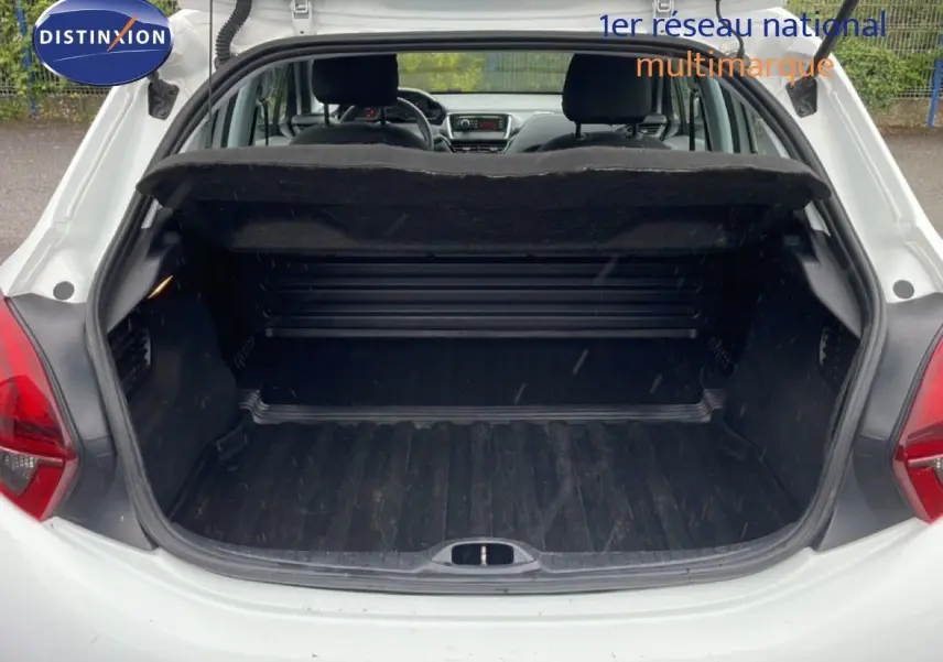 Coffre ouvert vu de l'arrière d'une Peugeot 208 Société blanc banquise, montrant l'espace de chargement vide.