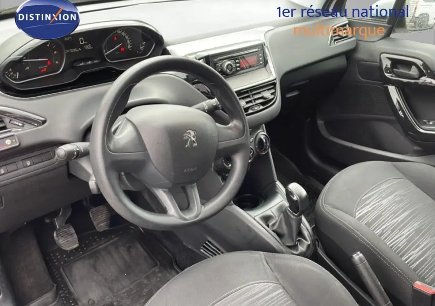 Vue intérieure de la Peugeot 208 Société 2018, tableau de bord et volant noirs avec détails tissu gris sur les sièges.