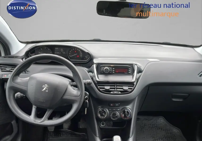 Vue intérieure avant centrée sur le tableau de bord et volant noir d'une Peugeot 208 Société blanc banquise de 2018.