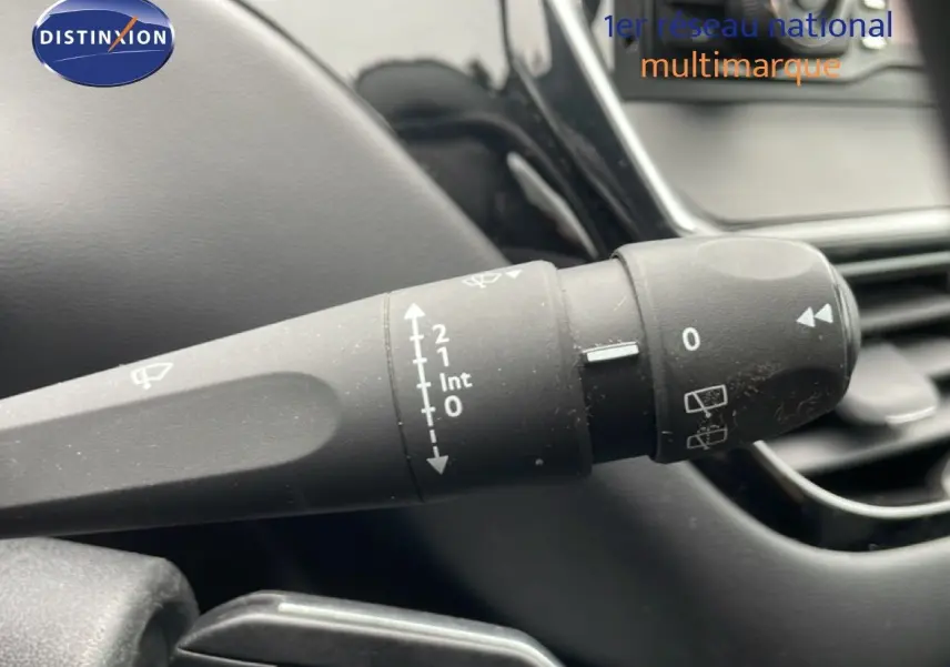 Gros plan sur la commande d’essuie-glace à gauche du volant dans l’habitacle noir d’une Peugeot 208 Blanc Banquise.