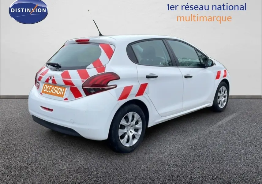 Vue 3/4 arrière droite d’une Peugeot 208 Société blanche avec marquages rouges et blancs, en stationnement sur sol gris.