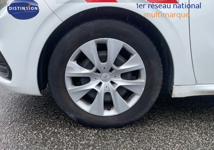 Gros plan sur la roue avant droite d'une Peugeot 208 Société blanche avec jante argentée et marquage rouge sur la carrosserie.