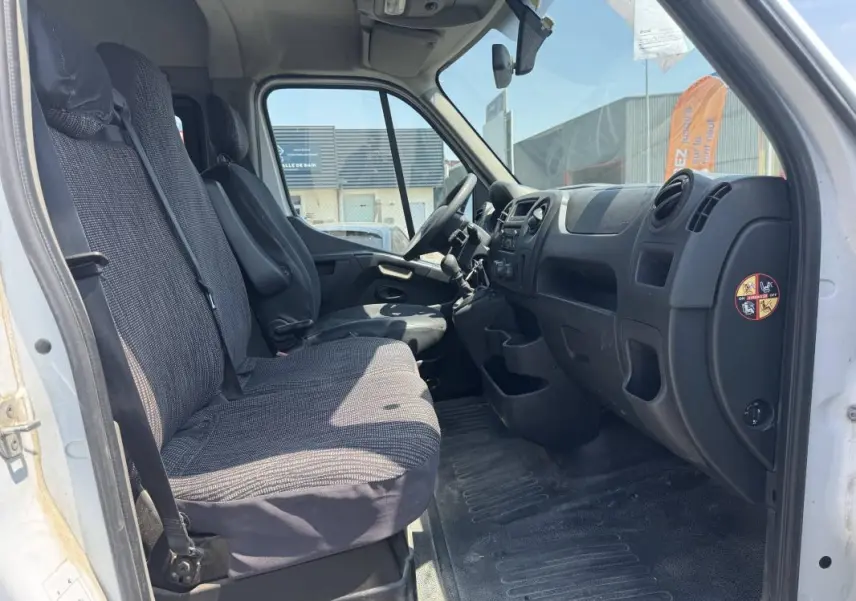 Vue intérieure côté conducteur du Renault Master blanc 2019, montrant les sièges avant et le tableau de bord noir.
