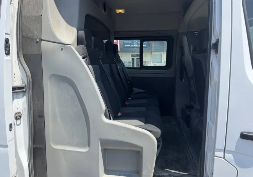 Intérieur du Renault Master blanc 2019, vue latérale sur la rangée de sièges passagers en tissu noir.