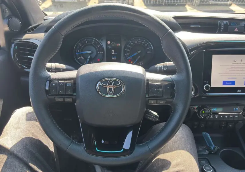 Vue rapprochée du volant cuir multifonctions du Toyota Hilux 2026 avec tableau de bord et écran multimédia JBL.
