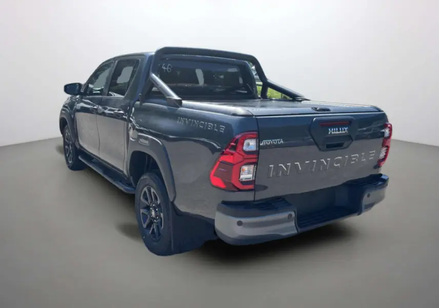 Toyota Hilux 4x4 gris atlas en 3/4 arrière droit, avec arceaux et rideau coulissant manuel sur la benne.