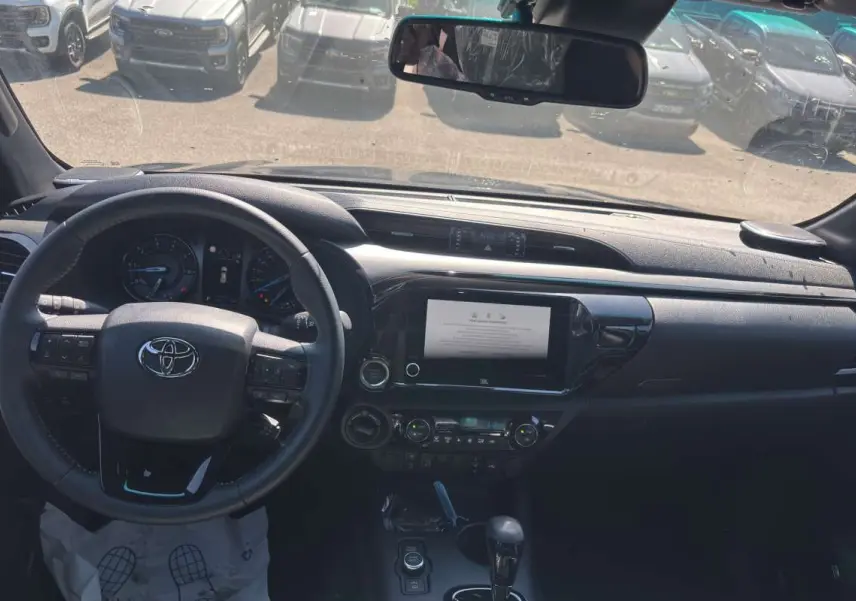 Vue intérieure du tableau de bord du Toyota Hilux 2026 gris atlas, volant cuir multifonctions et écran tactile central.