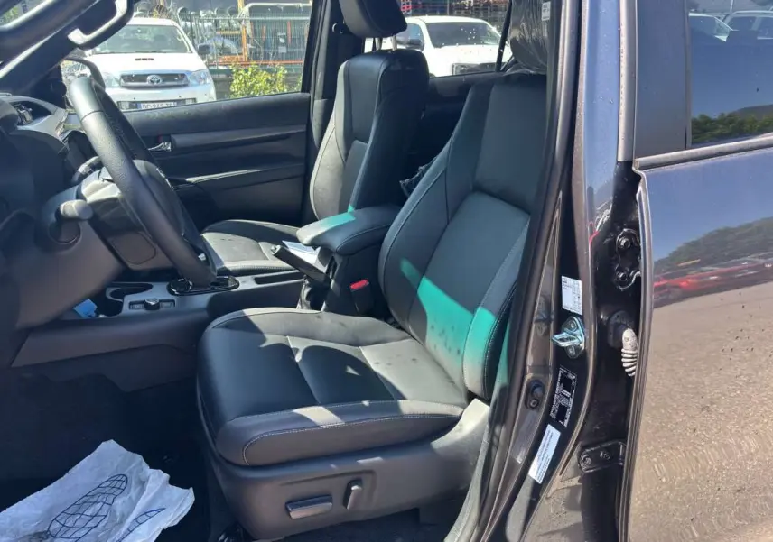 Vue intérieure côté conducteur du Toyota Hilux 4x4 gris atlas 2026, avec sièges cuir et volant multifonctions.