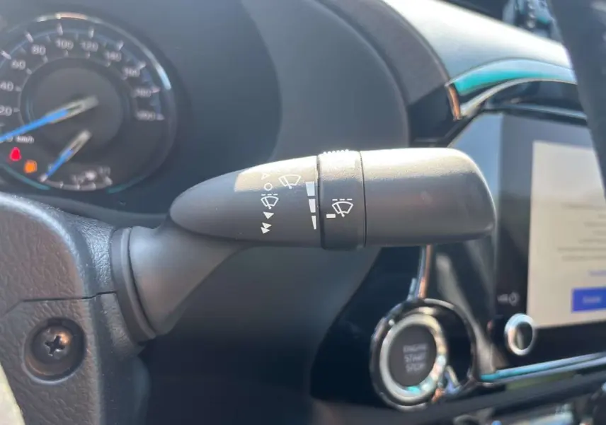 Gros plan sur la commande d’essuie-glace à gauche du volant cuir dans le Toyota Hilux 4x4 gris atlas 2026.