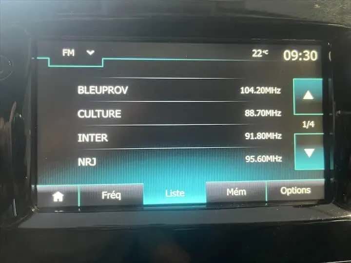 Écran tactile multimédia de la Renault Clio IV affichant la liste des stations FM avec température et heure visibles.