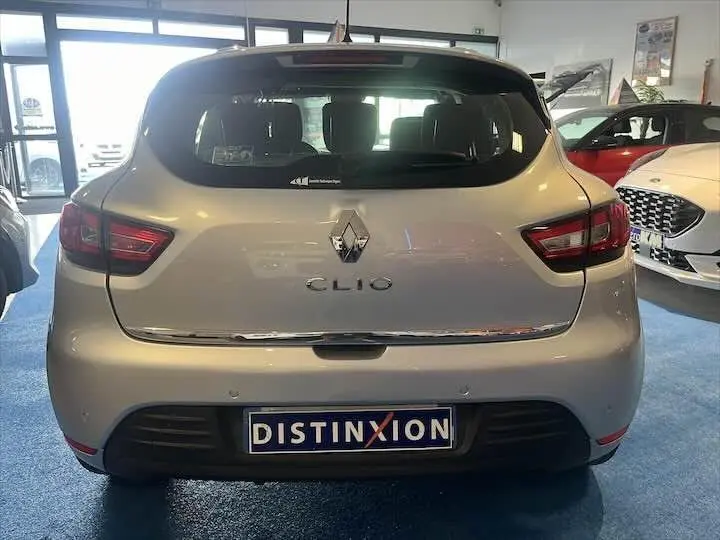Vue arrière d'une Renault Clio IV gris argent exposée en showroom avec plaque Distinxion visible.