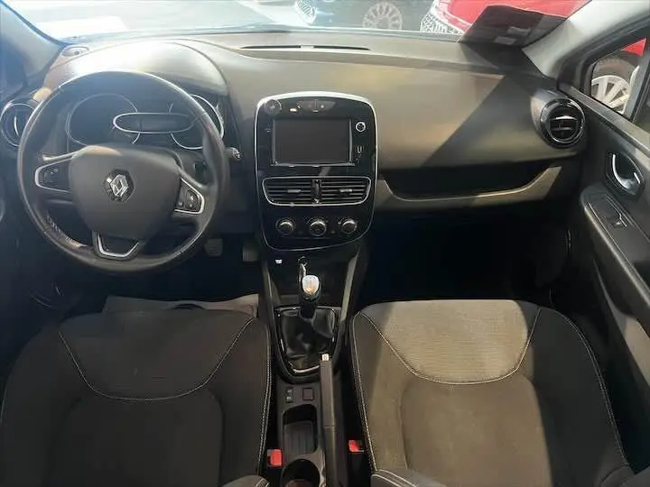 Intérieur de Renault Clio IV essence 2019, vue frontale du tableau de bord et des sièges noirs avec console centrale manuelle.