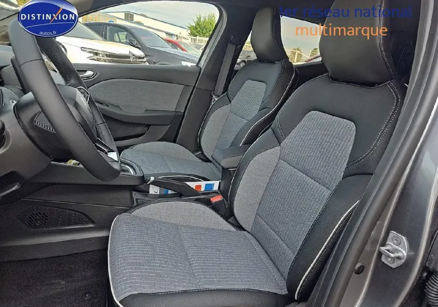 Intérieur avant côté droit de la Renault Clio V gris schiste, sièges tissu gris avec surpiqûres blanches visibles.