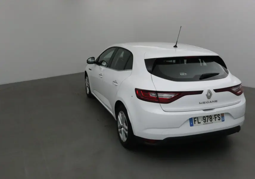 Vue 3/4 arrière droite d'une Renault Mégane IV berline blanche avec feux arrière allongés et antenne de toit.