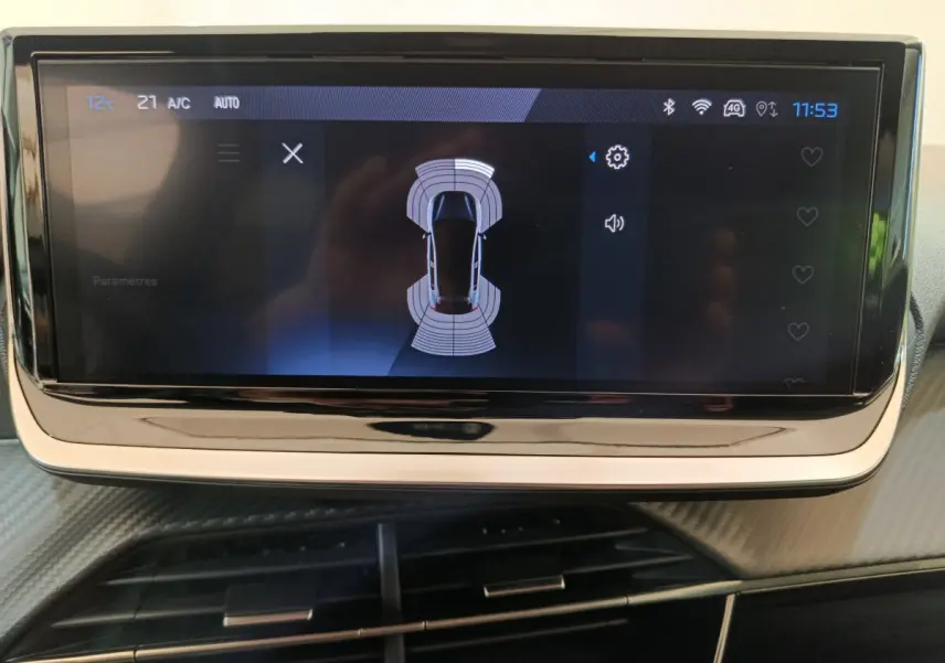 Écran tactile central affichant l'aide au stationnement sur Peugeot 208 gris clair, vue intérieure rapprochée