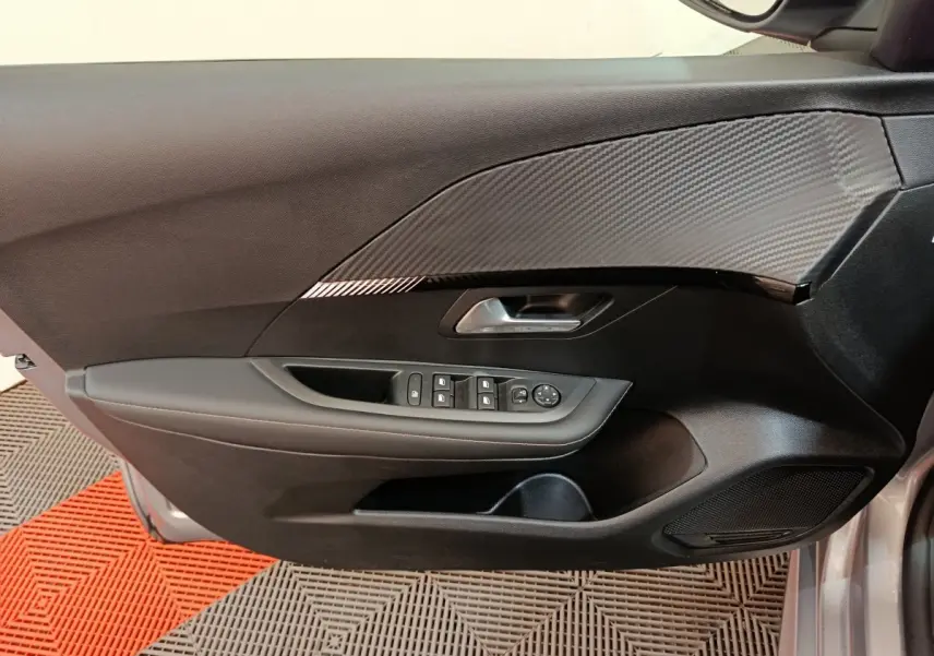 Gros plan sur la porte avant gauche gris clair de la Peugeot 208 avec commandes électriques et insert décoratif noir.