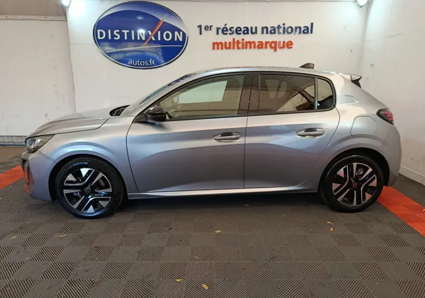 Profil côté gauche d'une Peugeot 208 PureTech 100 S&S Allure gris clair, roues alliage et vitres teintées visibles.