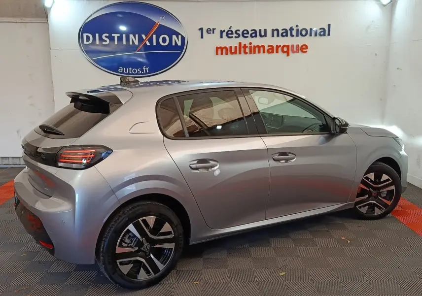 Vue latérale droite d'une Peugeot 208 PureTech 100 S&S Allure gris clair avec jantes alliage et vitres teintées.
