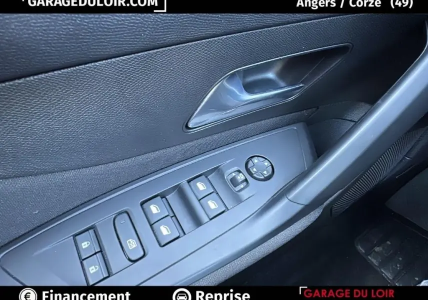 Détail de la porte côté conducteur de la Peugeot 308 gris clair 2023 avec commandes électriques des vitres et verrouillage.