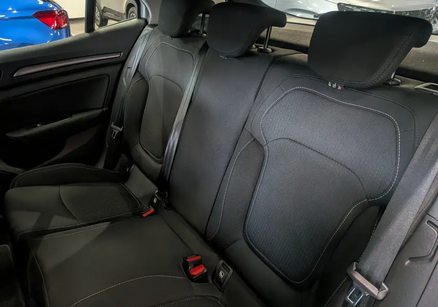 Vue intérieure sur les sièges arrière en tissu noir de la Renault Mégane IV Berline, avec ceintures de sécurité visibles.
