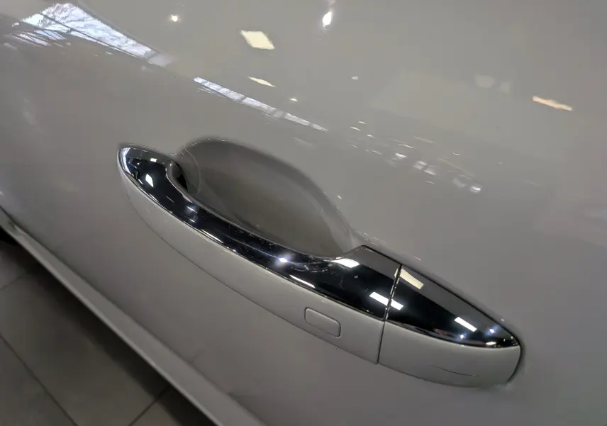 Poignée de porte chromée sur la portière côté gauche d'une Renault Mégane IV Berline Blanc Glacier 2021.
