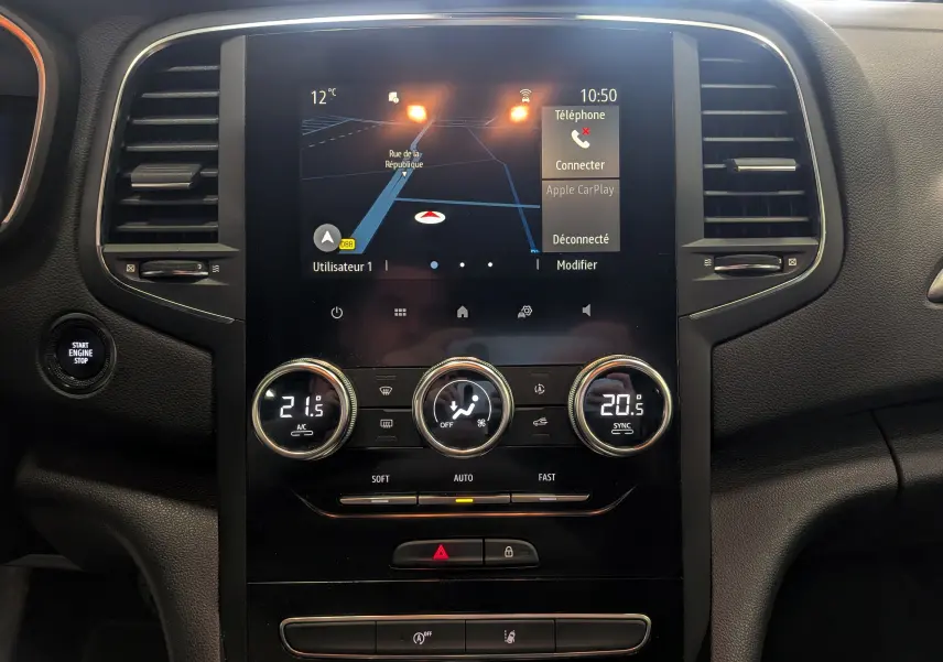 Vue rapprochée du tableau de bord de la Renault Mégane IV Berline 2021, écran tactile avec navigation et commandes de climatisation.