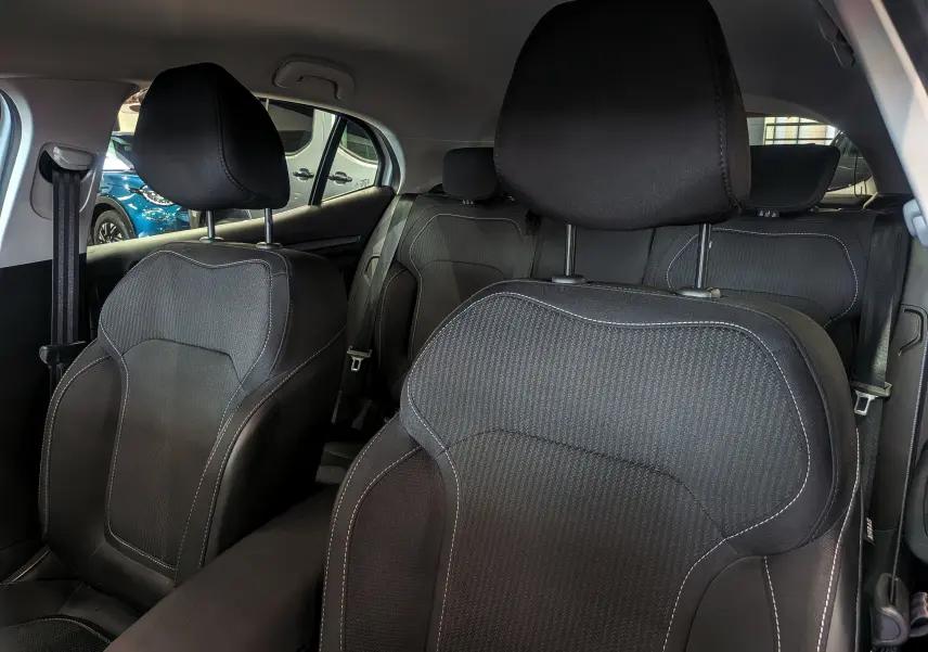 Vue intérieure centrée sur les sièges avant en tissu noir de la Renault Mégane IV Berline, avec arrière-plan lumineux.