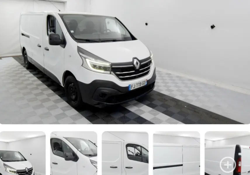 Renault Trafic Fourgon blanc vu en 3/4 avant droit dans un espace intérieur lumineux avec calandre noire.