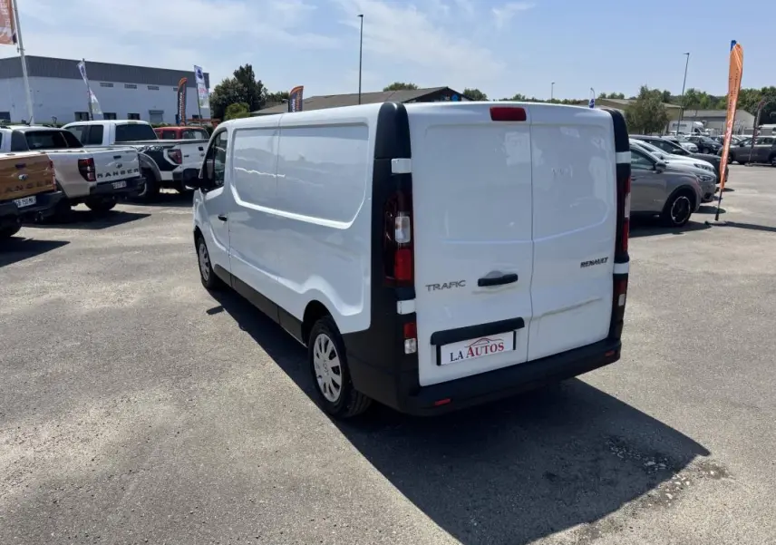 Vue 3/4 arrière droite d’un Renault Trafic Fourgon blanc 2019 avec portes arrière fermées sur parking.