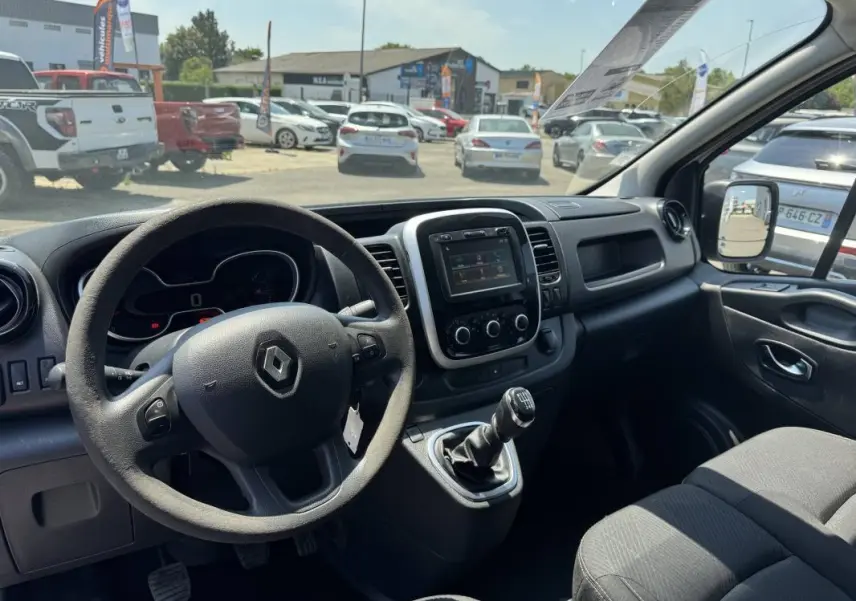 Intérieur du Renault Trafic Fourgon blanc 2019, vue côté conducteur montrant le volant, la console centrale avec écran tactile et levier de vitesses manuel.