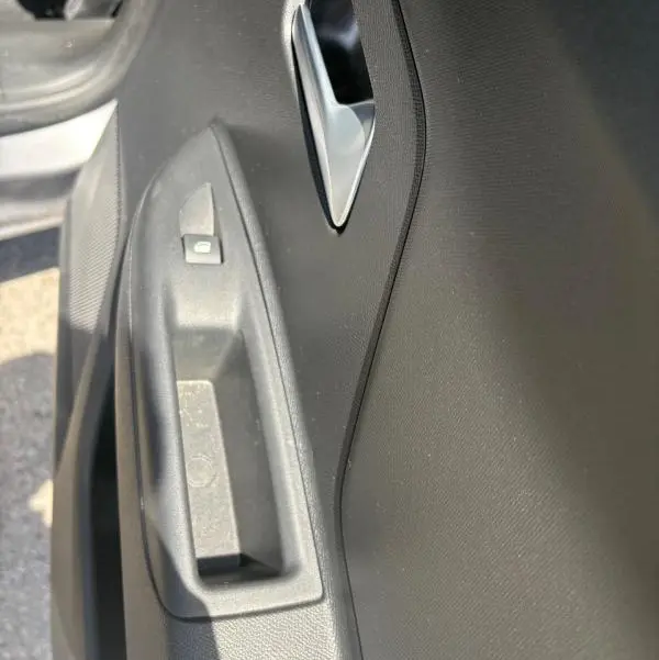 Gros plan sur la poignée intérieure et le bouton de verrouillage de la porte côté conducteur d’un Opel Mokka électrique gris.