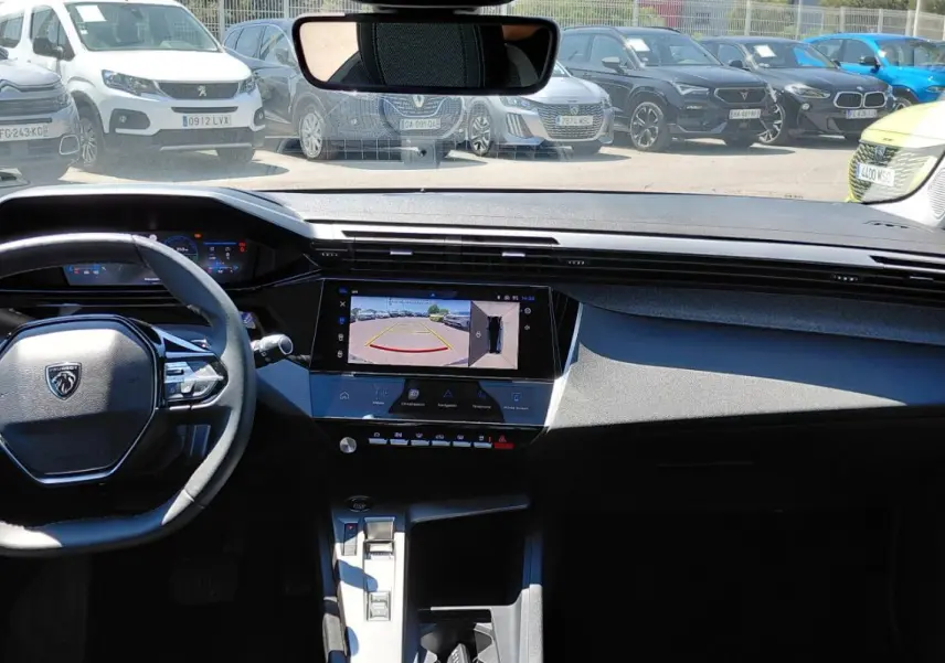 Vue intérieure frontale du tableau de bord de la Peugeot 308 SW Hybrid 145 gris, avec écran tactile affichant la caméra de recul.