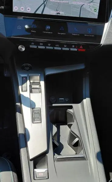 Vue plongeante sur la console centrale et l'écran tactile du Peugeot 308 SW Hybrid gris, avec levier de vitesse automatique et commandes digitales.