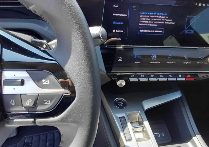 Vue rapprochée de l’intérieur de la Peugeot 308 SW Hybrid 145, montrant le volant, la console centrale et l’écran tactile.