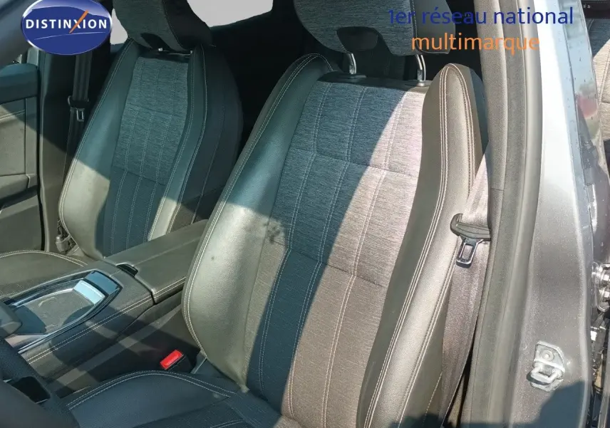 Vue intérieure montrant les sièges avant en cuir noir et tissu gris du Renault Austral gris schiste métal, côté gauche ouvert.