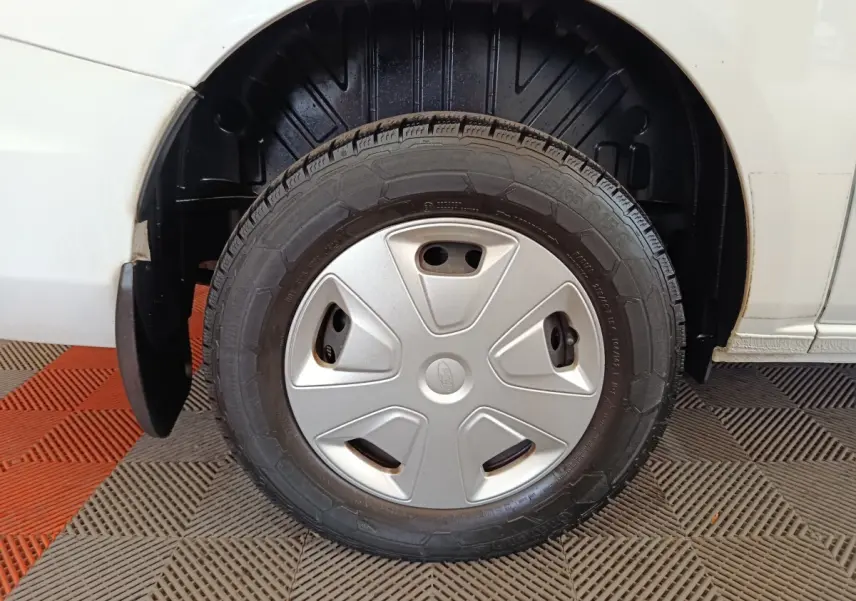 Gros plan sur la roue avant droite du Ford Transit Custom blanc, avec enjoliveur gris et pneu visible.