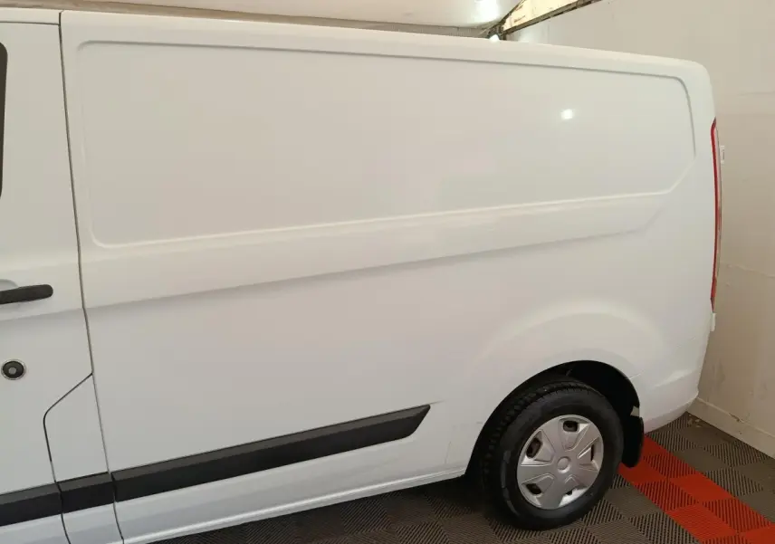 Vue latérale côté droit d'un fourgon Ford Transit Custom blanc, avec porte latérale pleine et jante acier.