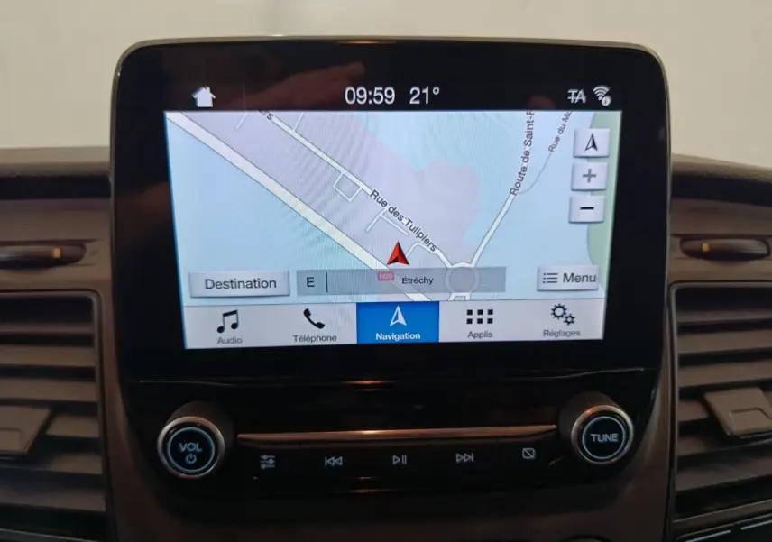 Écran tactile central du Ford Transit Custom blanc, affichant la navigation avec commandes audio en dessous.
