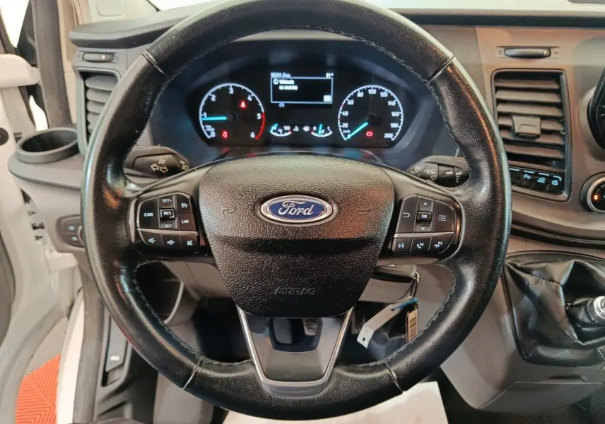 Vue rapprochée du volant en cuir noir et du tableau de bord digital du Ford Transit Custom blanc de 2020.