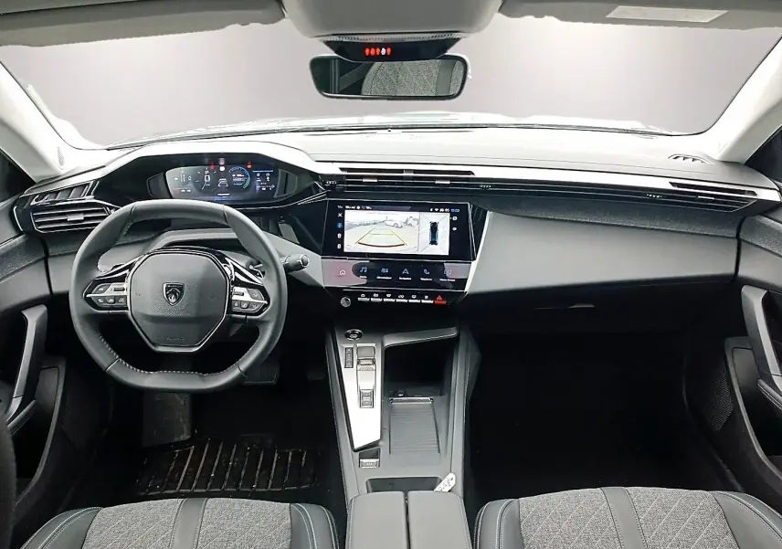 Vue intérieure avant de la Peugeot 408 Hybrid 145 allure 2024, tableau de bord noir avec écran tactile et volant multifonction.