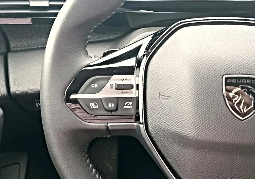 Gros plan sur le volant cuir noir multifonction de la Peugeot 408 Hybrid 145 allure, avec logo lion central.