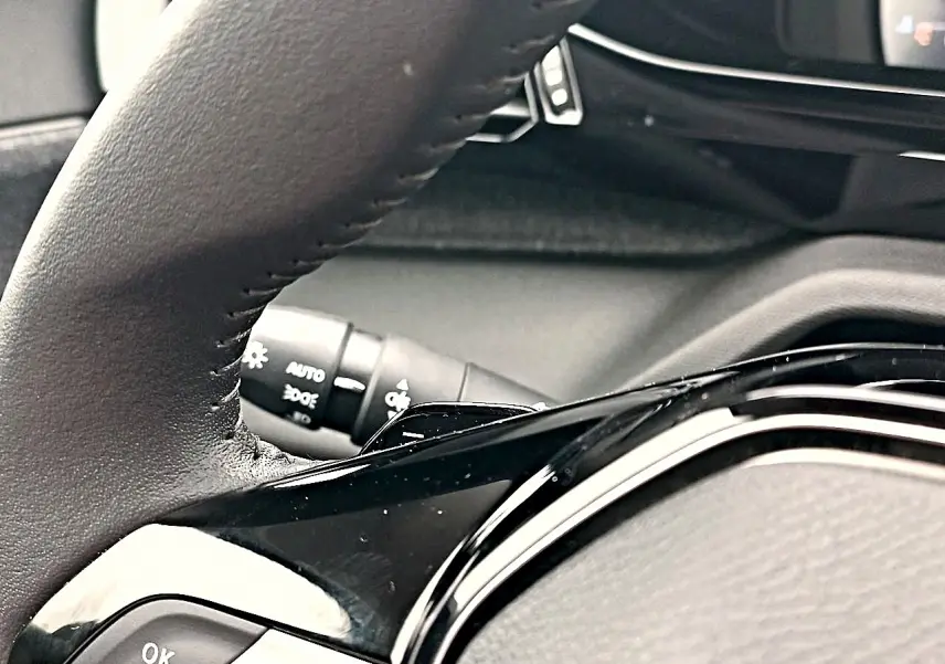 Gros plan sur le volant cuir noir multifonction de la Peugeot 408 Hybrid 145 allure 2024, avec commandes intégrées.
