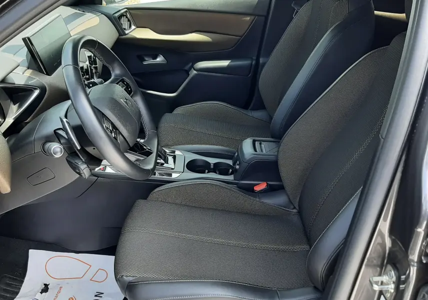 Vue intérieure côté conducteur du DS3 Crossback 2020, sièges noirs en tissu et cuir, tableau de bord moderne avec écran tactile.