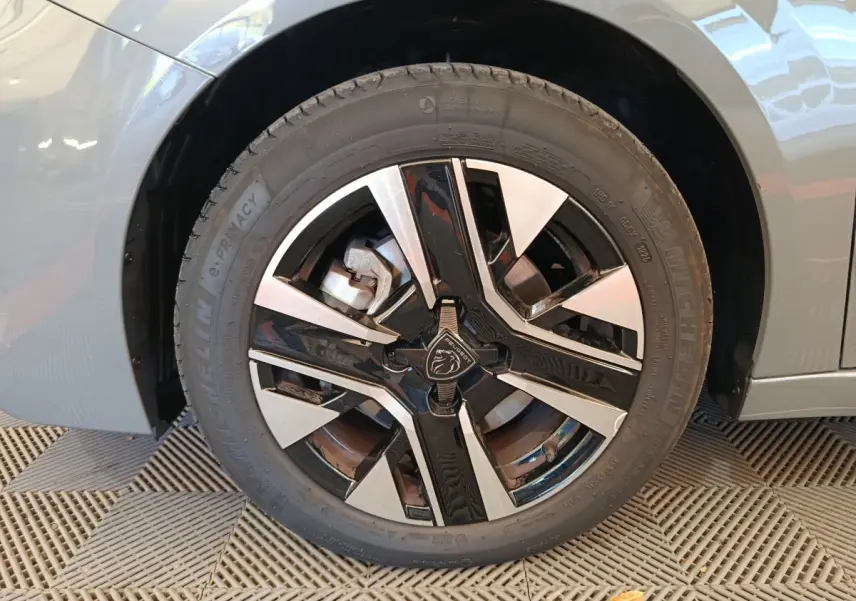 Gros plan sur la roue avant gauche gris foncé de la Peugeot 208 PureTech 100 S&S Allure avec jante noire et argentée.