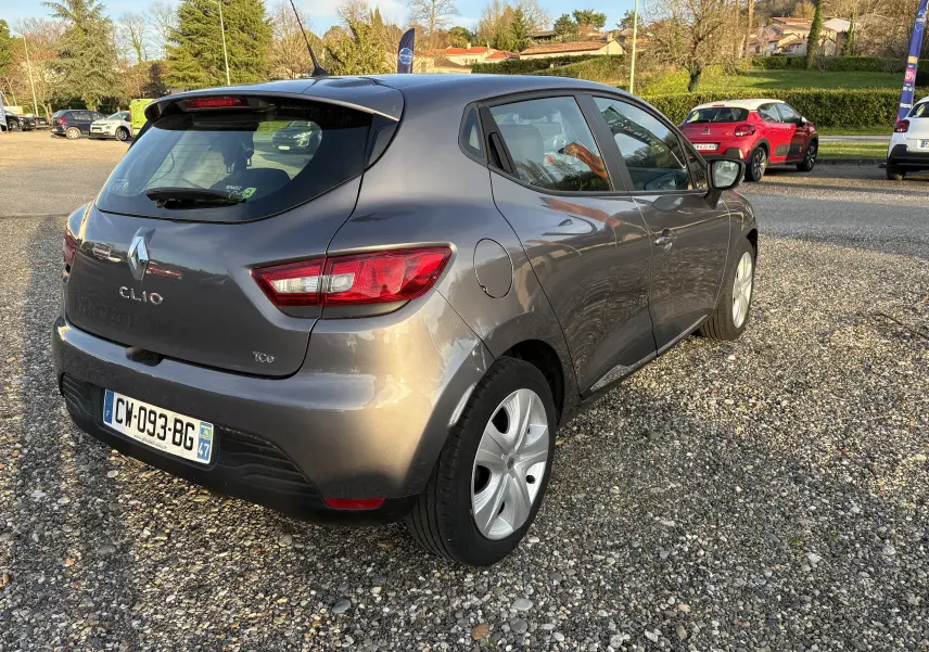 Vue 3/4 arrière droite d'une Renault Clio IV grise de 2013, avec feux arrière LED et jantes alliage visibles.
